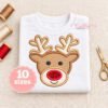 Boy reindeer applique stitched on a folded white shirt, with tan antlers, a cream muzzle, and a glitter red nose.