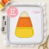 Candy corn applique stitched on white fabric inside a rectangular plastic machine embroidery hoop.