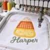 Floral and gingham candy corn applique with Harper embroidered below in sage thread beneath a multi-needle embroidery machine.