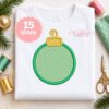 Christmas ornament applique embroidery design with green gingham fabric and gold ornament cap on white shirt