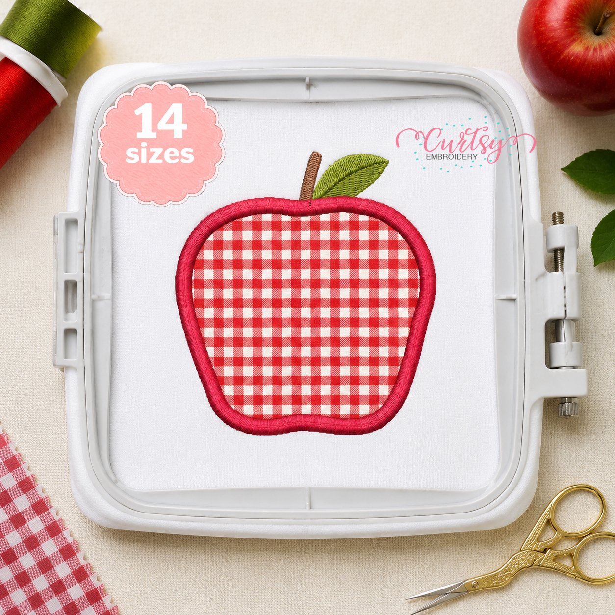 Red gingham apple applique embroidery design stitched in a white plastic machine embroidery hoop