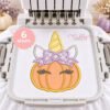 AI-assisted mockup of unicorn pumpkin appliqué with a lavender floral bow, peach dotted pumpkin, and yellow horn, hooped beneath a multi-needle machine with needles raised.