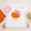 Pumpkin with bow applique on an open white girls shirt personalized with the embroidered name Maisie