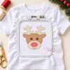 Boy reindeer embroidery design centered in a white plastic machine embroidery hoop, with the rest of the white shirt visible around it.