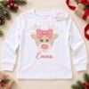 Full white long-sleeve shirt laid flat with the pink-bow reindeer embroidered on the front and the sample name Emma stitched beneath it in pink.