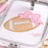 Football with bow embroidery design shown in a plastic machine embroidery hoop