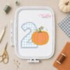 Number two pumpkin applique embroidery design displayed inside a plastic machine embroidery hoop.