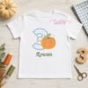 White birthday shirt featuring a number three pumpkin applique with an embroidered name and coordinating fall birthday props.