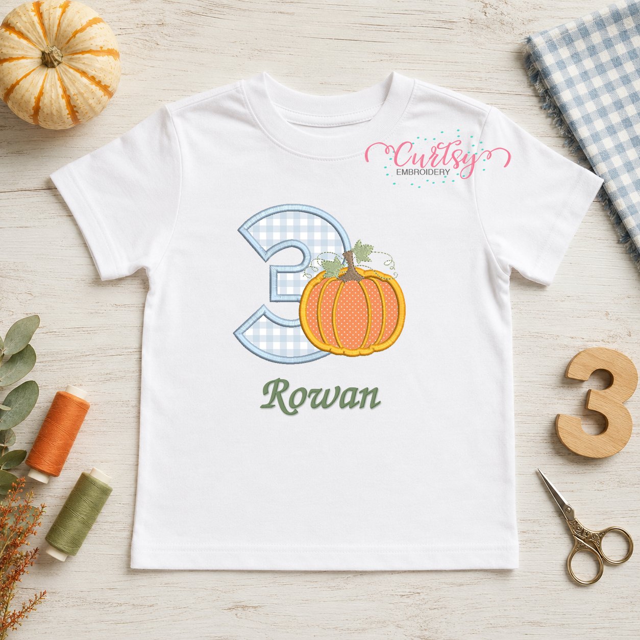 3rd Birthday Pumpkin Applique Design _ Logo 1 White birthday shirt featuring a number three pumpkin applique with an embroidered name and coordinating fall birthday props.