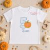 Lifestyle mockup of the 5th birthday pumpkin applique design with an embroidered name below.