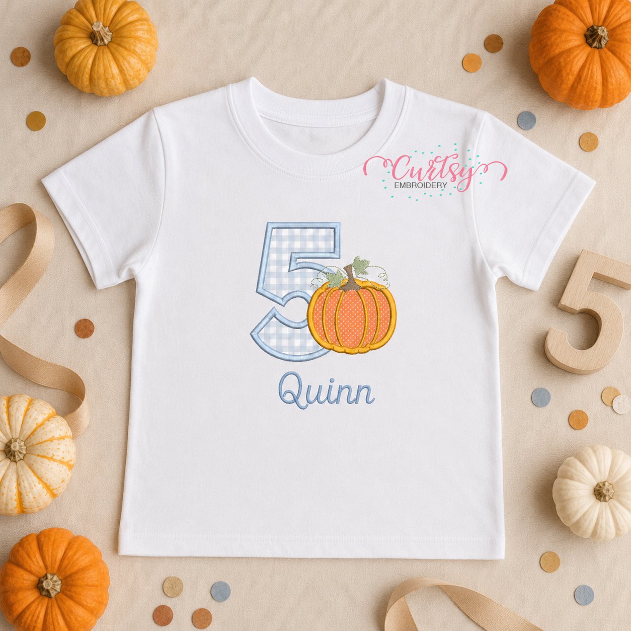Lifestyle mockup of the 5th birthday pumpkin applique design with an embroidered name below.