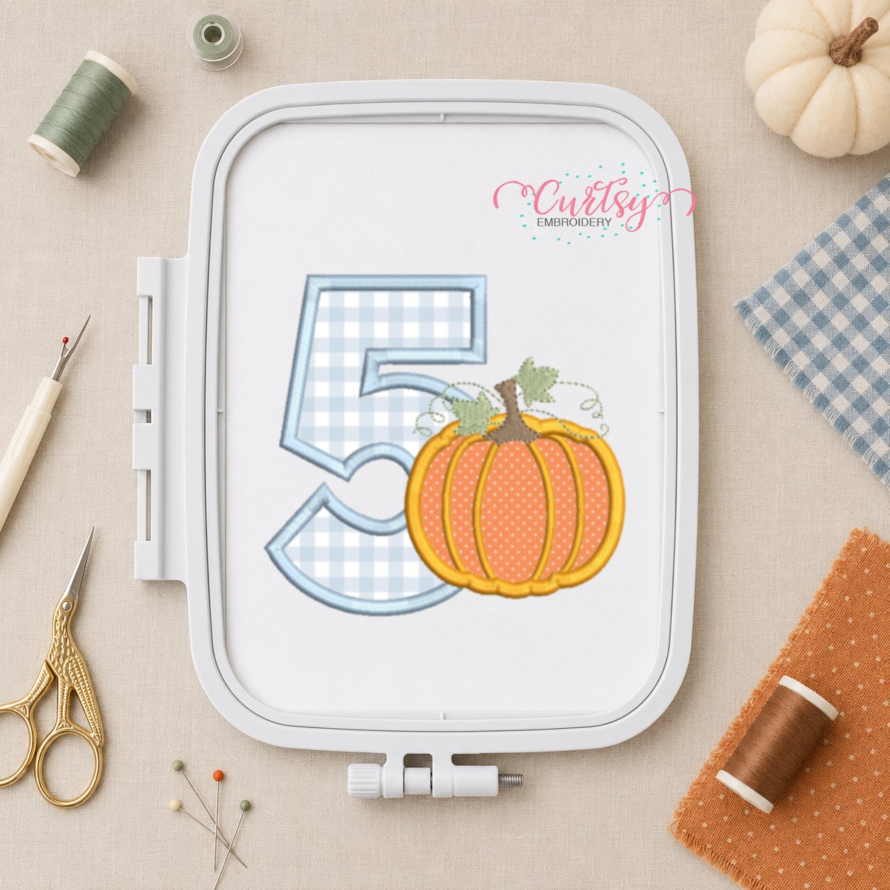 5th birthday pumpkin applique design displayed in a plastic embroidery machine hoop.