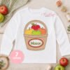 Apple Basket Monogram Applique embroidered on an open white shirt with the name Mason