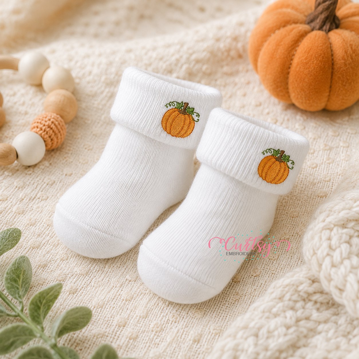Mini pumpkin embroidery design stitched on white baby sock cuffs