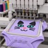 Multi-needle embroidery machine stitching the cat face applique design