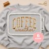 Coffee Weather applique embroidery design on a sweatshirt inside a rectangular plastic embroidery machine hoop