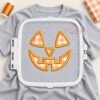 Jack O Lantern applique stitched on a gray shirt inside a rectangular white plastic embroidery machine hoop