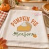 Pumpkin Pie Season Embroidery Design _ Logo 1 Pumpkin Pie Season embroidery design stitched on a kitchen towel in a warm fall kitchen