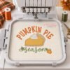 Pumpkin Pie Season Embroidery Design _ Logo 2 Pumpkin Pie Season embroidery on a cream towel in a plastic hoop with thread, scissors and fall props