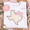 Texas with bow applique embroidery design on folded white shirt