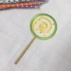 20261030_142120 Real machine embroidery stitch-out of the lollipop applique showing the fabric center, decorative spiral stitching, satin stitch border, and embroidered stick on fabric.