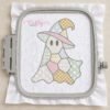 Digital mockup of a pastel patchwork ghost wearing a witch hat, embroidered on white fabric inside a gray plastic machine embroidery hoop, with decorative stitch patterns and thin gray outlines.